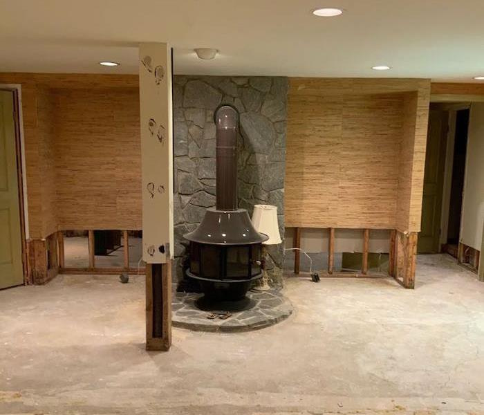 Basement with bare floor and stone fireplace in the background