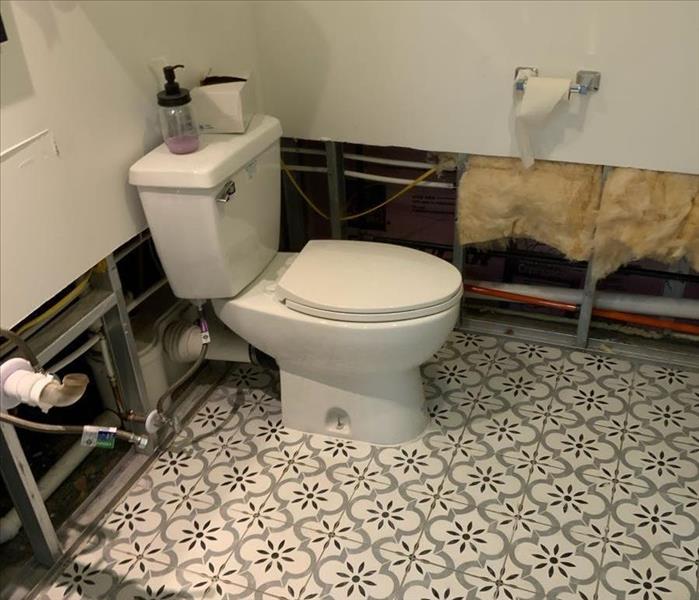 Bathroom with partially removed walls and a white toilet