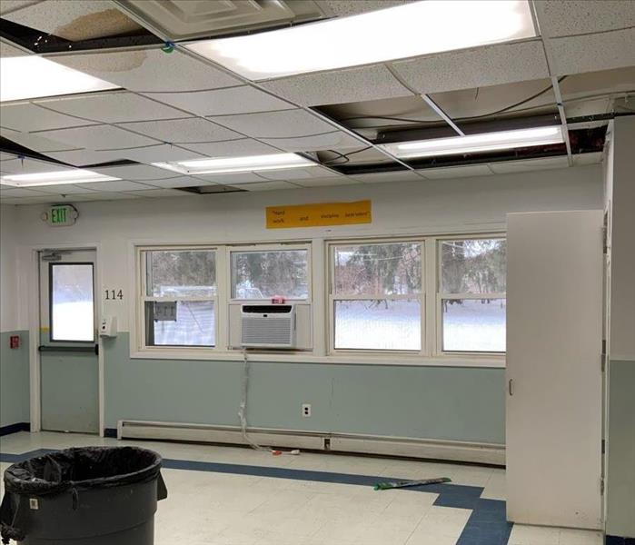 Classroom with window air conditioner unit and ceiling tiles with water spots