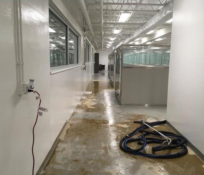 Office walkway with cubicles and water on concrete floor with hose